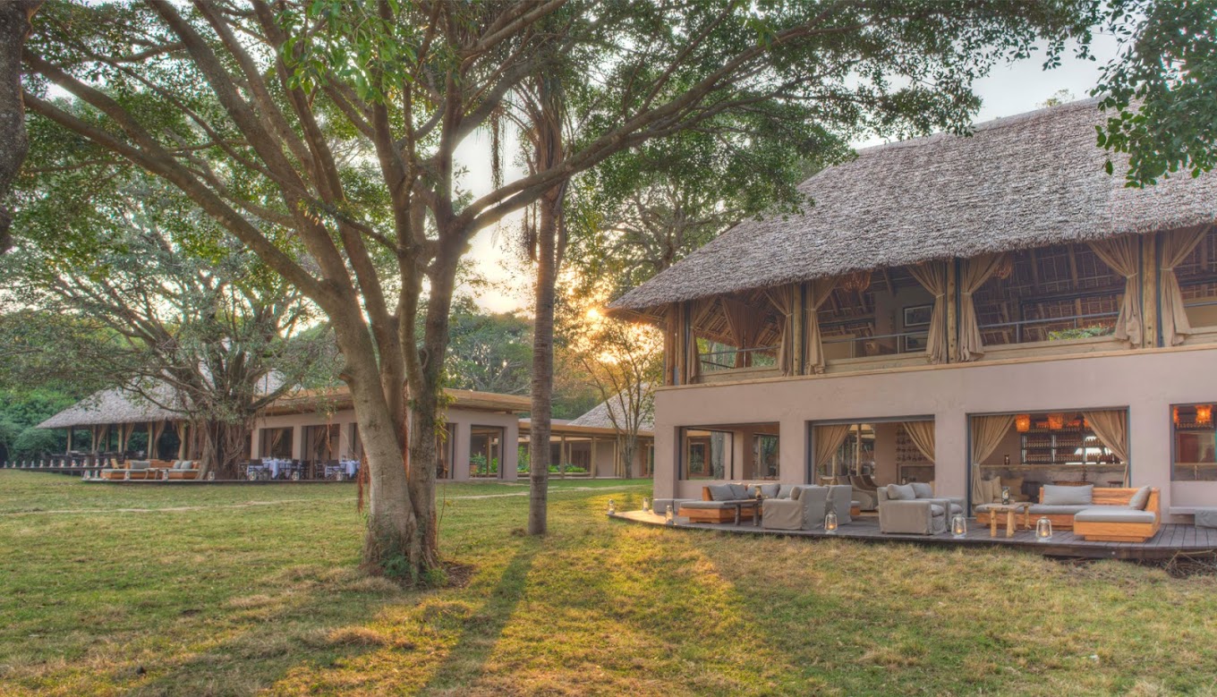 The dining room at the safari lodge, with wooden tables, chairs, and large windows overlooking the savanna in Kichwa tembo