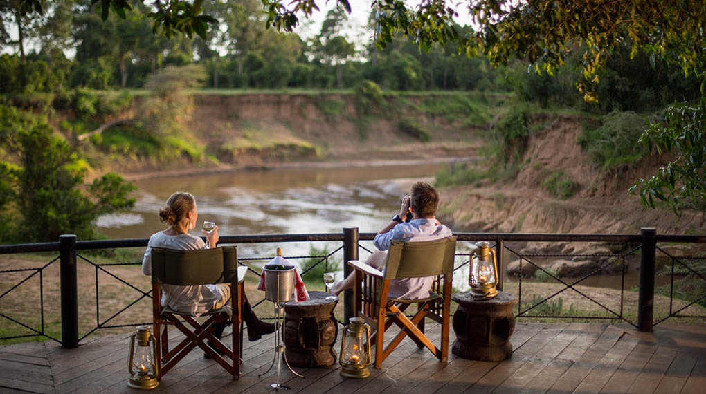 A pair of people seated on chairs by the river at Governors Camp