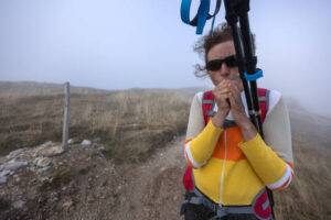 Woman Mature Hiker forget her thermal hiking gloves at home - cold temperature occur in High Mountains in off season