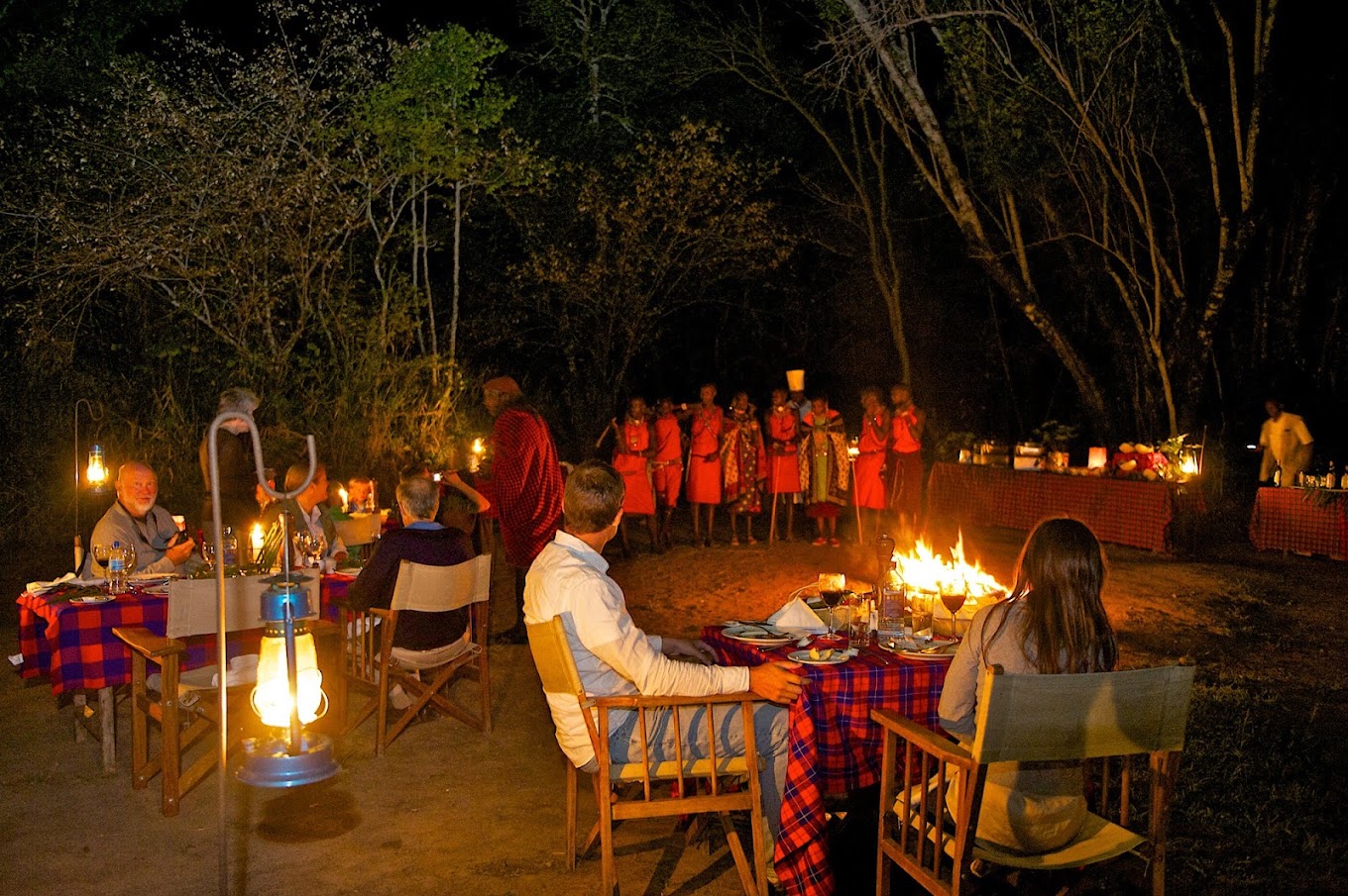  A group of Tourists sitting around a campfire at night at being entertained by Maasai's in Mara Intrepids Camp.