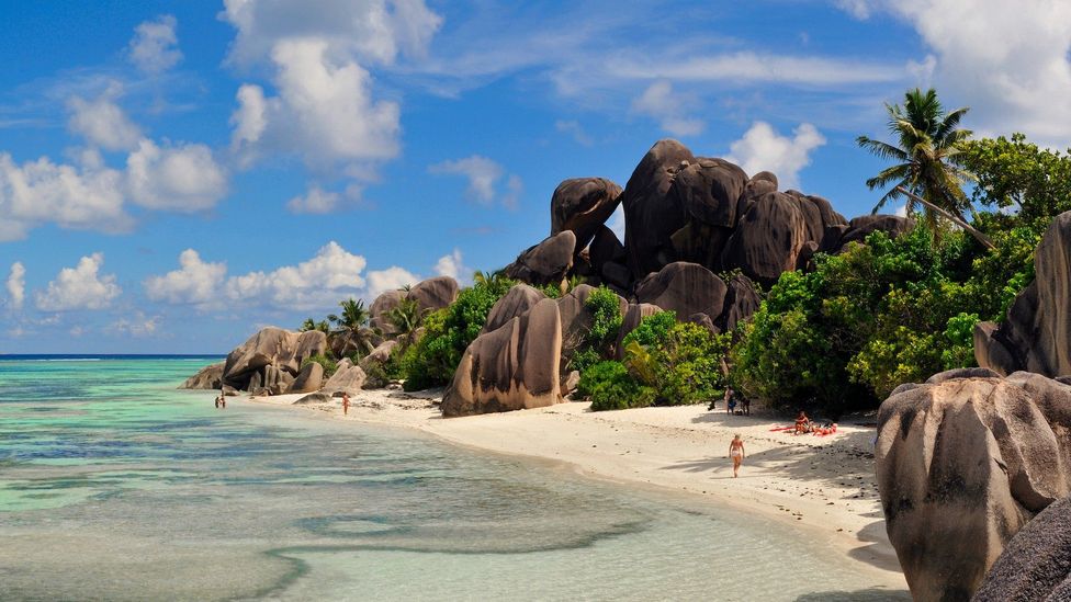 Anse Bonnet Carre Beach in Seychelles, featuring a rocky shoreline and lush trees.