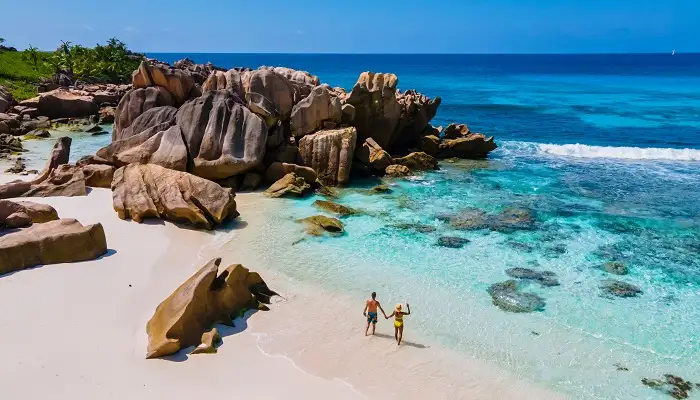Couple strolling by rocks at Anse Coco Beach.