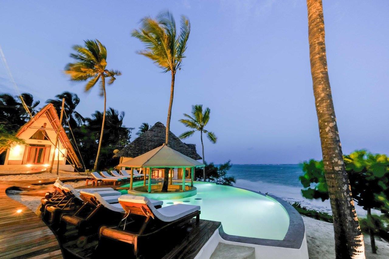 A serene Michamvi-Kae Beach at dusk, featuring lounge chairs and a tranquil pool, creating a peaceful atmosphere.