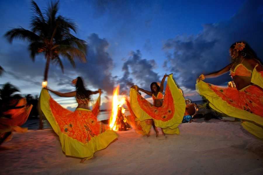 A group of people dancing on the beach. Cultural Experiences: Celebrating with traditional dances by the sea.