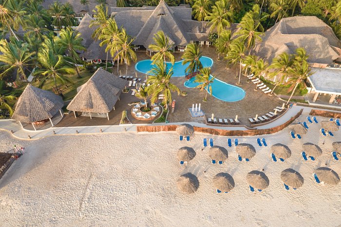 Aerial view of Kiwengwa Beach resort featuring charming thatched huts nestled among lush greenery and sandy shores