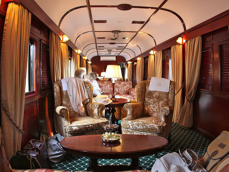 A luxurious train car featuring a plush couch and elegant chairs, designed for a comfortable travel experience.
