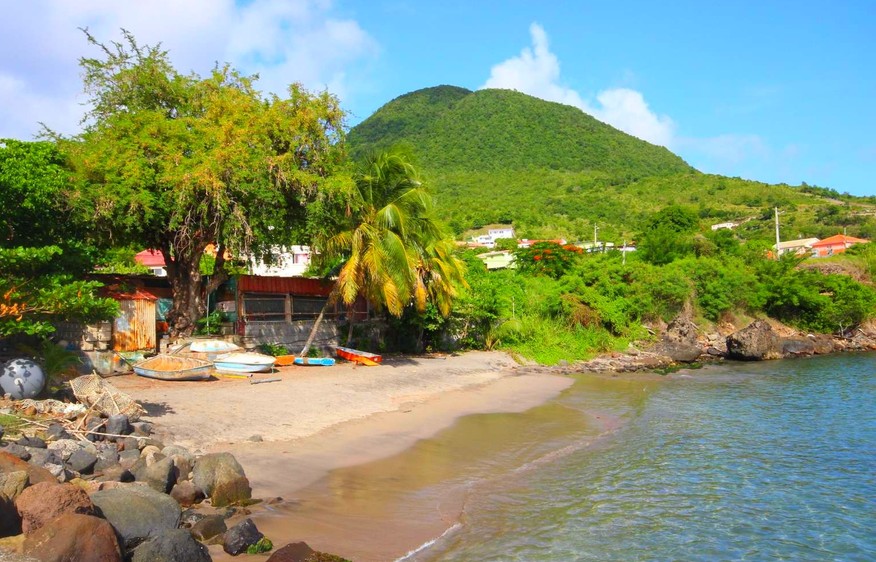 Stunning view of Petite Anse Beach in Seychelles featuring rocks, trees, and a mountain.
