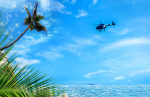 Commercial helicopter flying over tropical island and clear sky