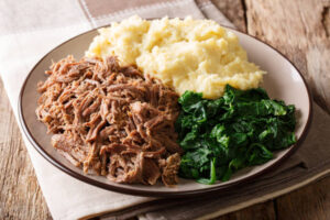 Botswana festive meal: seswaa stewed beef with pap porridge and spinach close-up on a plate on a table. horizontal