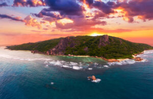 Aerial sunset view of Anse Source D'argent beach at the La Digue Island, Seychelles, with colorful clouds, palm trees and amazing granite rock formations.