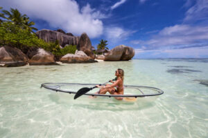 Happy woman enjoying while canoeing during summer day at sea. Copy space.