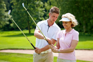 Male golf pro teaching female golfer the proper grip at golf course