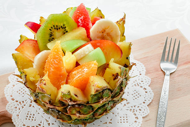 Fresh fruit salad with kiwi, banana, peach, orange, red orange, apricot and melon in handmade pineapple bowl.