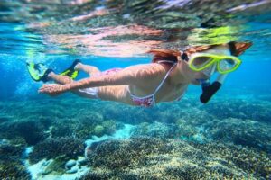 Woman snorkeling in ocean with mask at Sainte Anne Marine National Park.